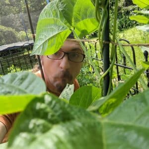 A photo of Avdi peering through bean plants in his garden