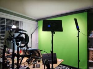 A photo of Avdi's desk/studio setup with green screen, many studio lights and a cluttered desktop